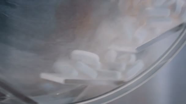 Visão de close-up de pílulas brancas em recipiente rotativo na farmácia — Vídeo de Stock