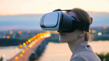 Kadın sanal gerçeklik gözlük güneş battıktan sonra şehirde kullanır
