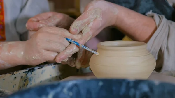 Potter showing how to work with ceramic in pottery studio