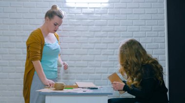 İki profesyonel kadınlar dekoratörler, kraft kağıt ile çalışma tasarımcılar