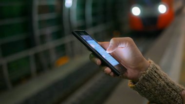 Metro istasyonunda akıllı telefon kullanan bir kadın.