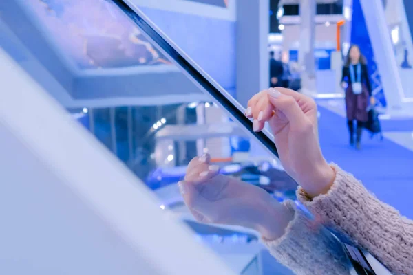 Woman using interactive touchscreen display at technology exhibition