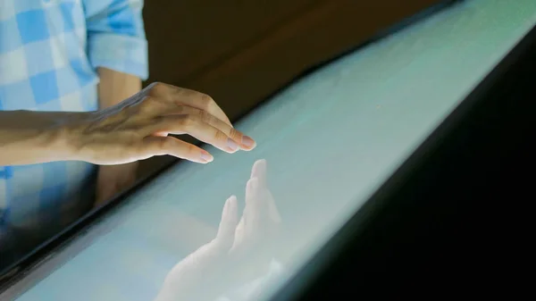 Woman using interactive touchscreen display at modern museum