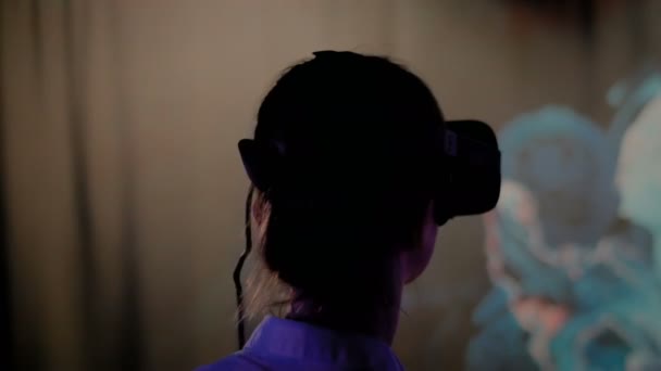 Jeune femme utilisant casque de réalité virtuelle à l'exposition interactive sombre — Video