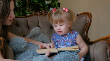 Genç anne ve bebek kızı okuma kitabını evde