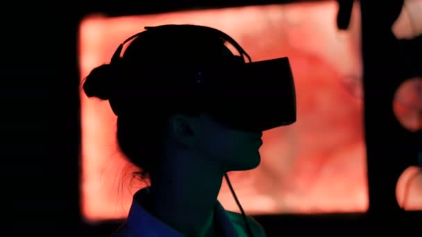 在黑暗互动展览中使用虚拟现实耳机的年轻女性 — 图库视频影像