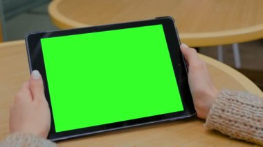 Evde yeşil ekranlı tablet bilgisayara bakan bir kadın