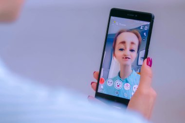 Akıllı telefonda yüz maskesi ile Snapchat Multimedya mesajlaşma uygulamasını kullanan kadın