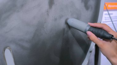 Mıknatıs sopalı kadın demir kum parçacıklarını kontrol ediyor