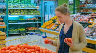 Bakkaldan taze kırmızı domates alan kadın.