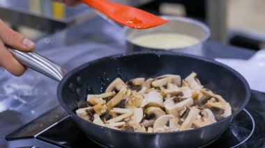 Şampiyon mantarlar tavada kızarıyor ve cızırdıyor.