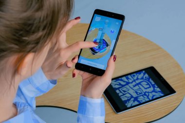 Artırılmış gerçeklik uygulaması ile akıllı telefon kullanan ve bina modeli yerleştiren kadın