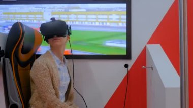 Sanal gerçeklik gözlüğü kullanan ve etrafa bakınan genç bir kadın.