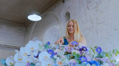 Çiçekçi, çiçekçide büyük bir çiçek sepeti yapıyor.