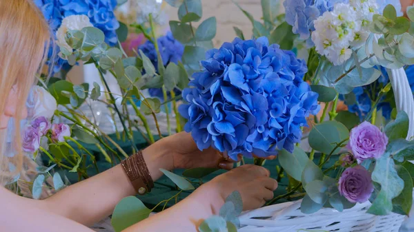 Florist making large floral basket with flowers at flower shop