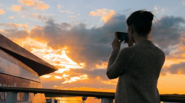 Kadın siluet alarak fotoğraf Günbatımı ile smartphone gemisi güvertede