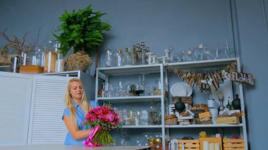 Profesyonel çiçekçi stüdyoda buketi tutuyor ve kontrol ediyor.