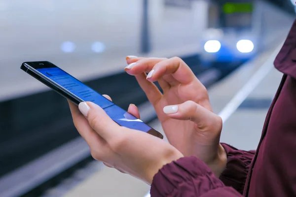 Woman using smartphone on subway platform