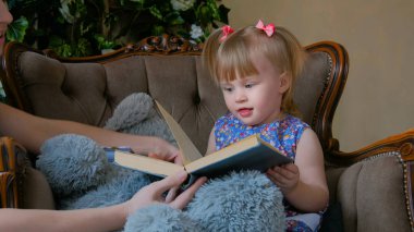 Genç anne ve bebek kızı okuma kitabını evde