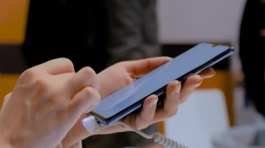 Kadın müşteri elektronik mağazasında akıllı telefon yeni model test