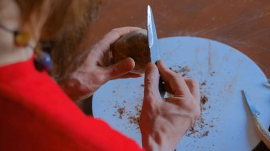 Profesyonel çömlekçi, çömlek atölyesinde özel bir aletle kuru kil bardağı şekillendiriyor.