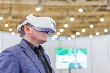 Sanal gerçeklik kulaklığı kullanan ve etkileşimli video sunumu izleyen adam