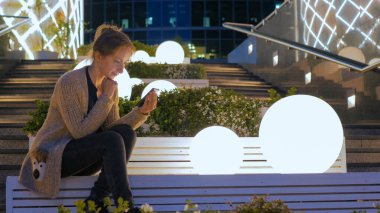 Smartphone şehirde geceleri kullanan kadın