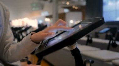 Kadın eli dokunmatik ekranı kullanarak yerde duran siyah tablet büfesi kullanıyor.