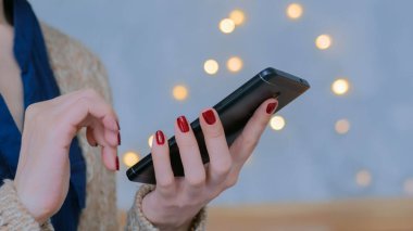 Evde dikey siyah akıllı telefon kullanan bir kadın