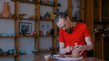 Profesyonel çömlekçi, çömlek atölyesinde özel bir aletle kuru kil kavanozunu şekillendiriyor.