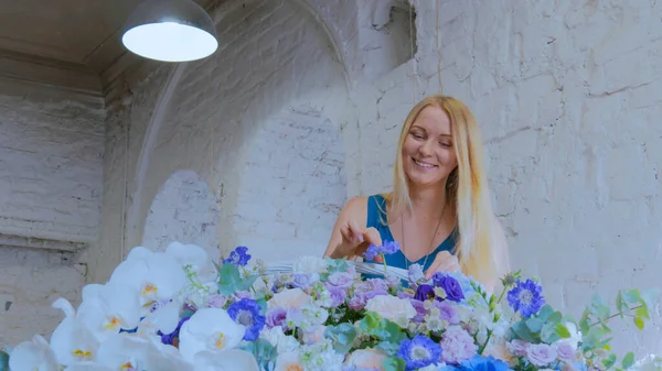 Florist making large floral basket with flowers at flower shop