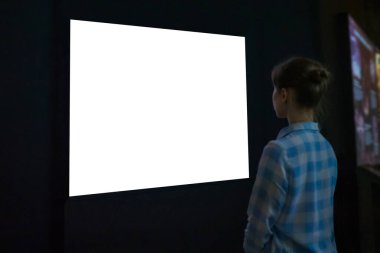Woman looking at white empty large wall display - mockup image