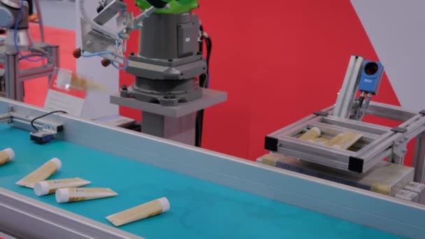 Emici bardaklı robotik kol manipülatörleri fuarda krem tüpleri hareket ettiriyor — Stok video
