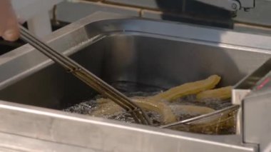 Yavaş çekim: Aşçı sokak gıda pazarında kaynamış yağ içinde churros pişiriyor: