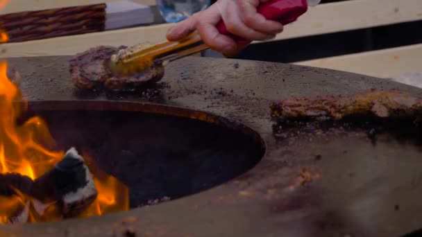 Movimento lento: Chef grelhar bifes de carne e costeletas no braseiro com chama quente — Vídeo de Stock