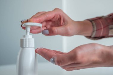 Kadın avuç içine antiseptik jel sıkıyor. Yan görüş kapalı.