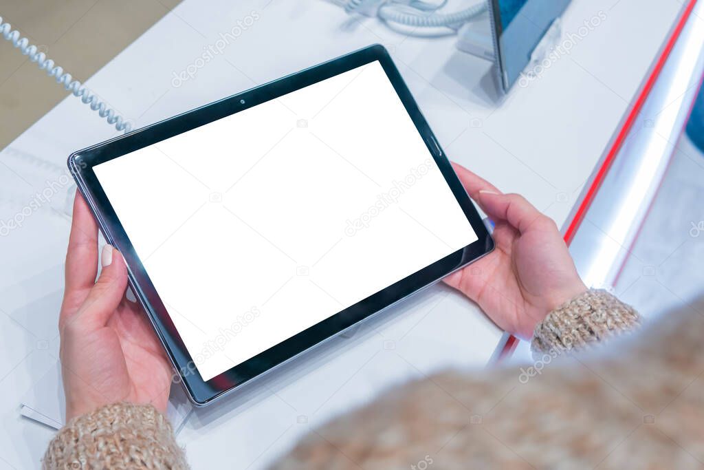 Woman holding tablet device with blank white display at electronic shop, store