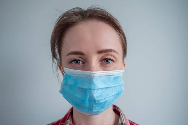 Woman wearing medical face mask, looking at camera - quarantine concept