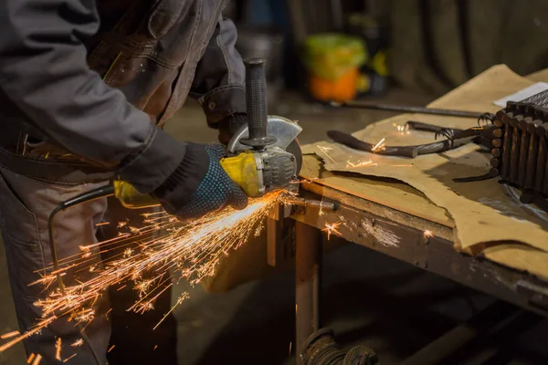 Demirci el testeresiyle metal kesiyor.