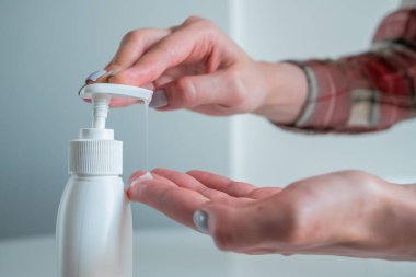 Kadın avuç içine antiseptik jel sıkıyor. Yan görüş kapalı.