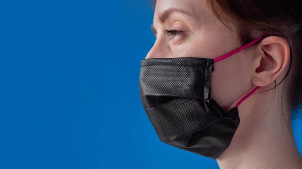 Close up - woman wearing medical face mask, looking away - quarantine concept