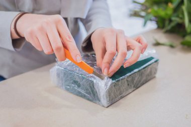 Çiçekçi çiçekçide çiçek aranjmanı için vahayı çiçeklerle süslüyor.