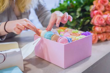 Manzarayı kapat - çiçekçi çiçekçi dükkanında çiçek ve kurabiye kutusu yapıyor.