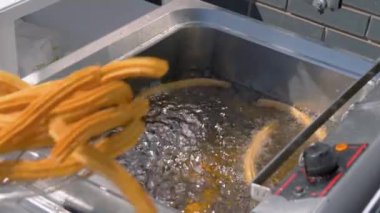 Yavaş çekim: Aşçı sokak gıda pazarında kaynamış yağ içinde churros pişiriyor: