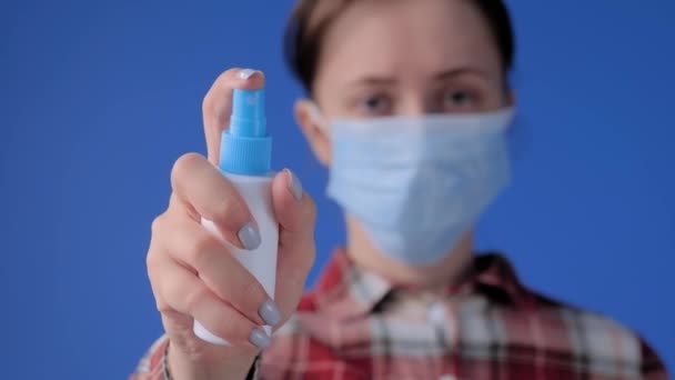 Slow motion: woman in face mask spraying antiseptic toward camera - close up — Stock Video