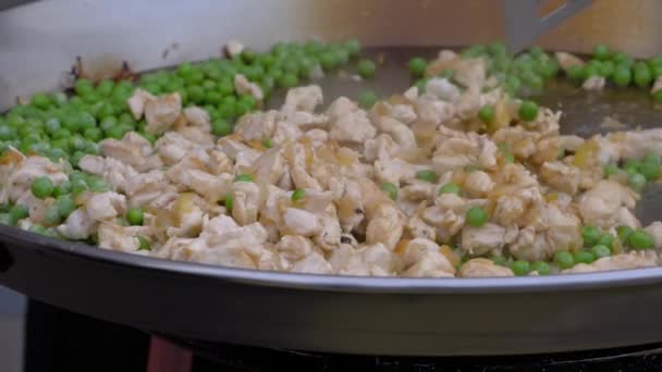 Mouvement lent : chef cuisinier cuisiner des morceaux de viande de poulet, petits pois dans un grand wok - vue rapprochée — Video