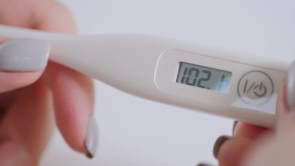 Nahaufnahme: Frau hält digitales medizinisches Thermometer mit hoher Temperatur — Stockvideo