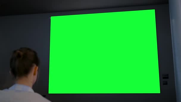 Groen scherm concept - vrouw op zoek naar grote lege interactieve groene display — Stockvideo