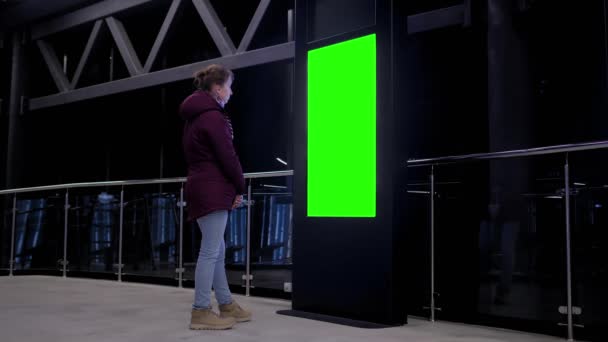 Concepto de pantalla verde - mujer mirando en blanco quiosco pantalla verde en la exposición — Vídeos de Stock