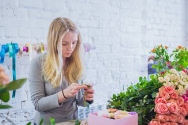 Çiçekçide çiçeklerle hediye kutusu yapan profesyonel bir çiçekçi.